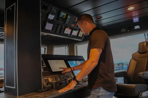 Marble engineer operating a touchscreen at the bridge console of a vessel
