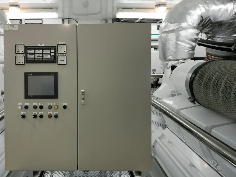 Engine Control System cabinet with touch display, analogue gauges and push buttons next to a diesel engine in the engine room