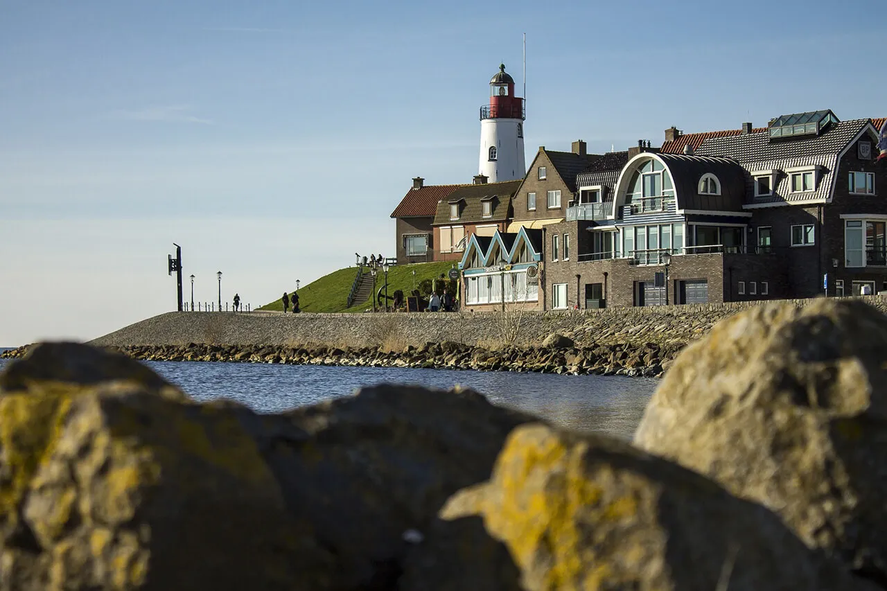 Lighthouse and dike houses of Urk seen from the rocky shore
